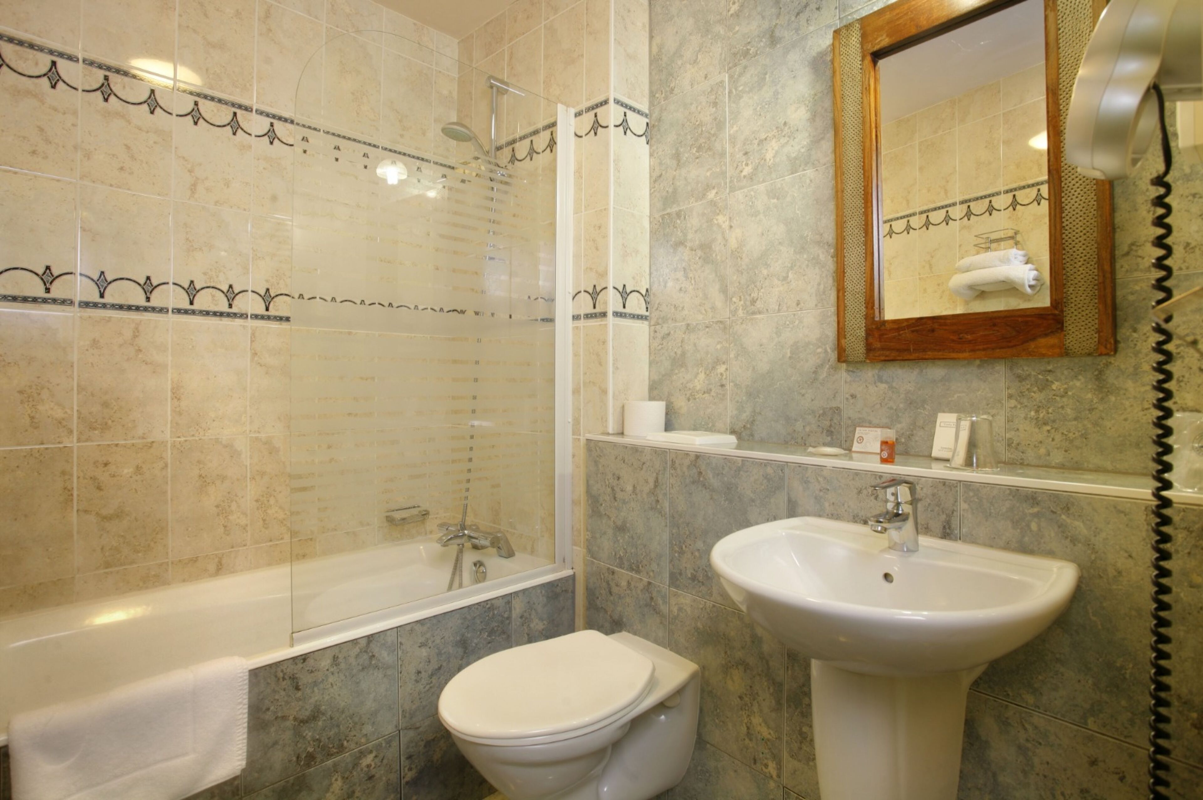 Ein Badezimmer mit Badewanne, Toilette, Waschbecken und einem Spiegel, an dem ein Handtuch hängt.