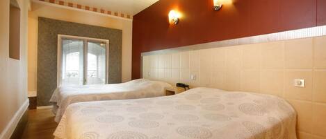 Habitación de hotel con dos camas, una ventana y una lámpara fijada a la pared.