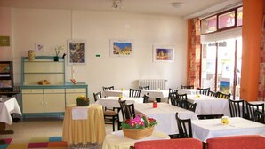 Un espace repas avec des tables et des chaises, un buffet et des œuvres d’art accrochées aux murs.