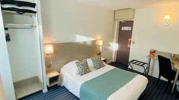 Habitación de hotel con cama, lámparas de noche, escritorio, silla y armario.
