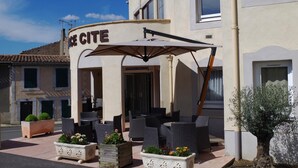 A hotel exterior with outdoor seating, a covered patio, and a sign reading "HOTEL CITY". - Hotel Espace Cité (Carcassonne)