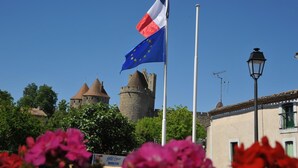 A historic building with a tower and a flagpole with the European Union flag and a national flag. - Hotel Espace Cité (Carcassonne)