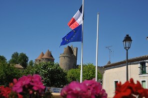 A historic building with a tower and a flagpole with the European Union flag and a national flag. - Hotel Espace Cité (Carcassonne)