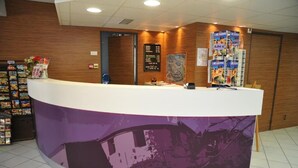 A reception desk with a curved design, a bulletin board, and a display of brochures. - Hotel Espace Cité (Carcassonne)