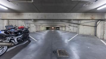 Um estacionamento com paredes de concreto e uma motocicleta estacionada em primeiro plano.