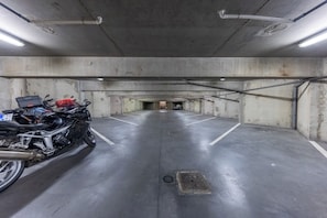 A parking garage with concrete walls and a motorcycle parked in the foreground. - Hotel Espace Cité (Carcassonne)
