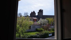 A view of a historic castle with a moat and a small building in the foreground. - Hotel Espace Cité (Carcassonne)