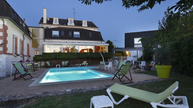 A swimming pool with lounge chairs and a patio area in a residential setting. - Hôtel Les Tilleuls, Bourges (Bourges)