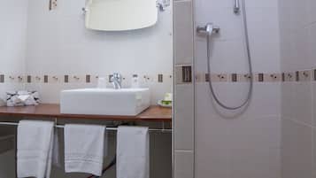 Une salle de bain équipée d’un lavabo, d’un miroir, d’une douche et d’une baignoire.