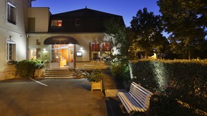 A hotel entrance with a reception desk, steps leading up to the door, and a bench in the foreground. - Hôtel Les Tilleuls, Bourges (Bourges)