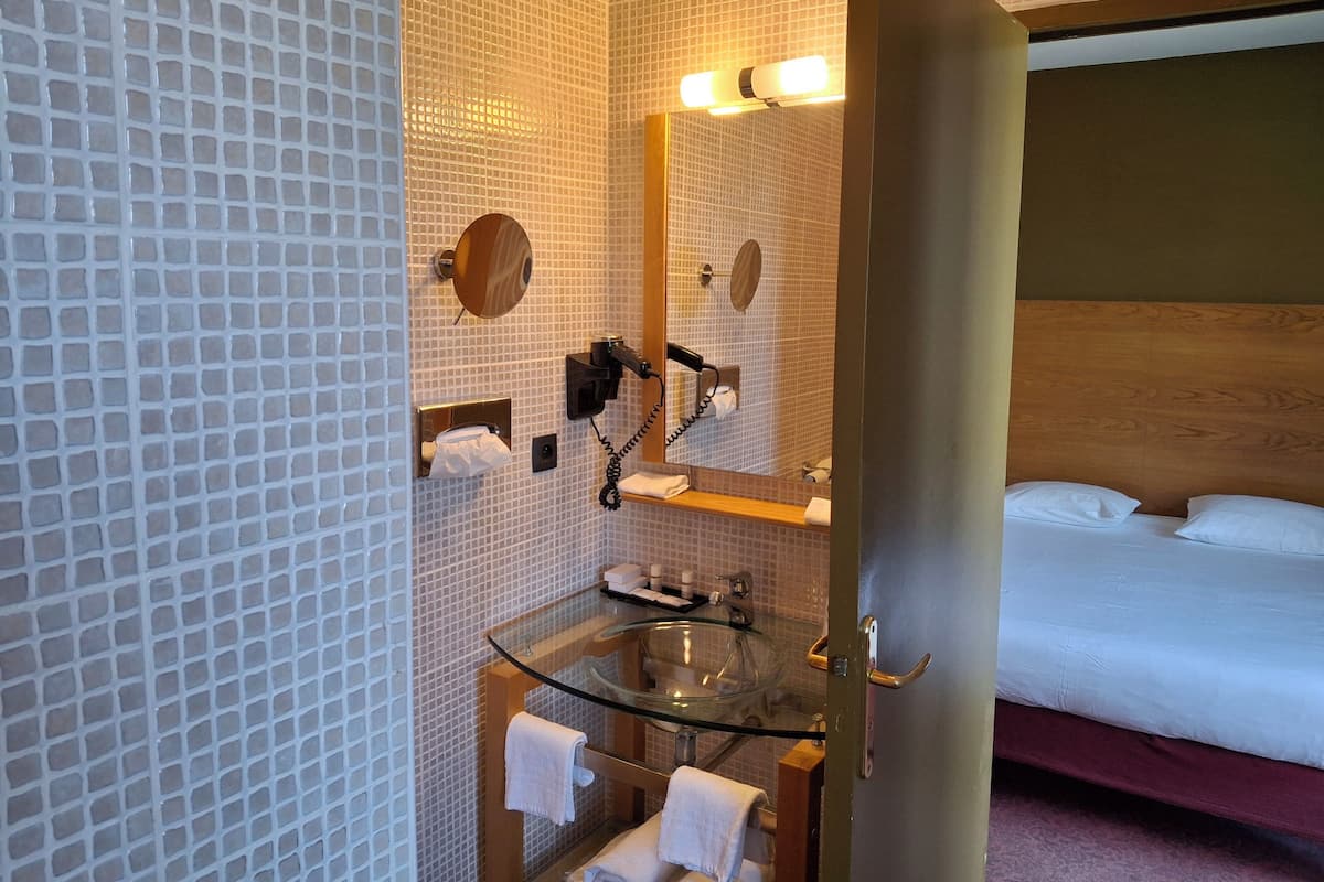 Relax in a stylish room with a large bed, glass-enclosed vanity, and a glass-topped sink.