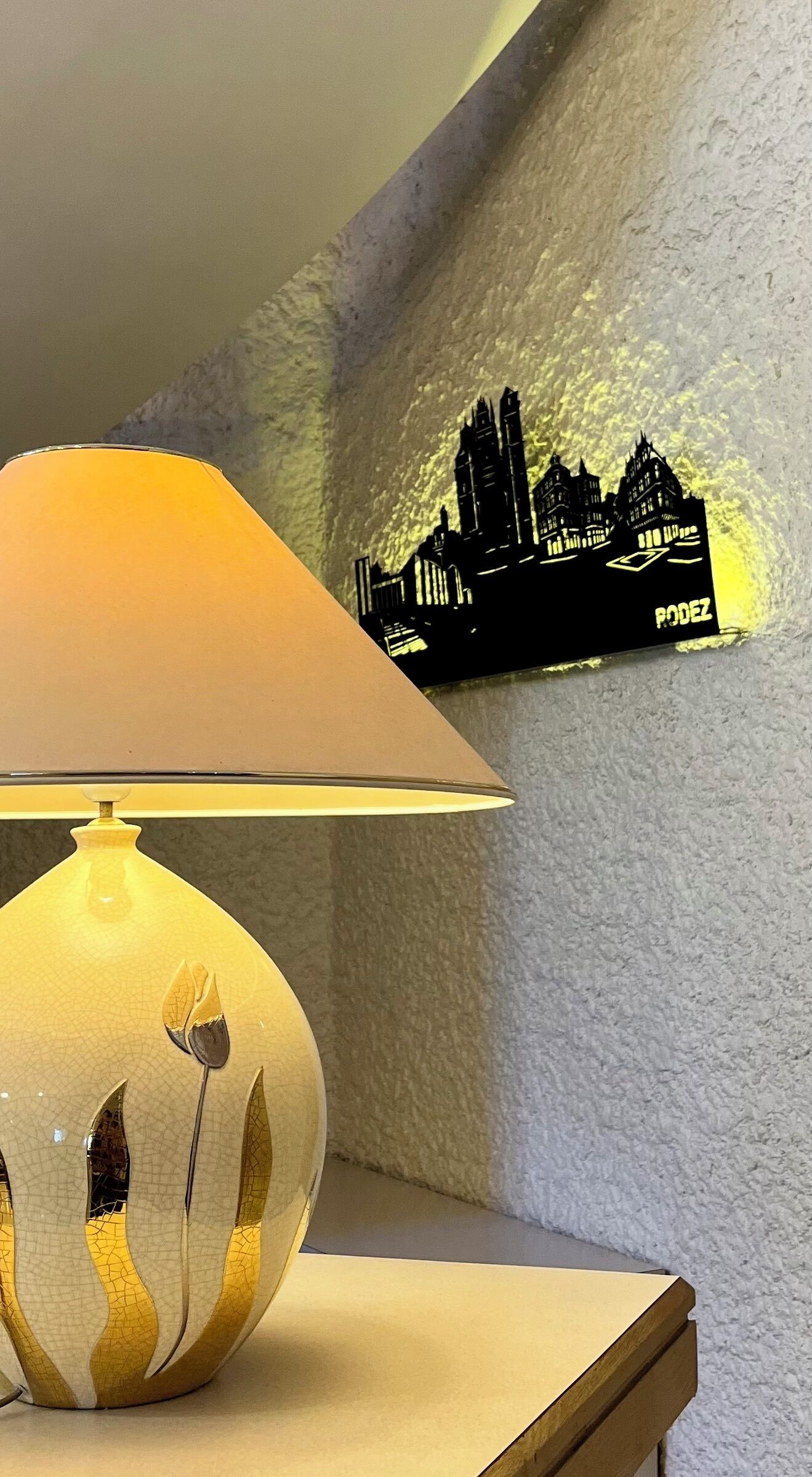 Een lamp met een geribbelde voet en een gele lampenkap op een nachtkastje.