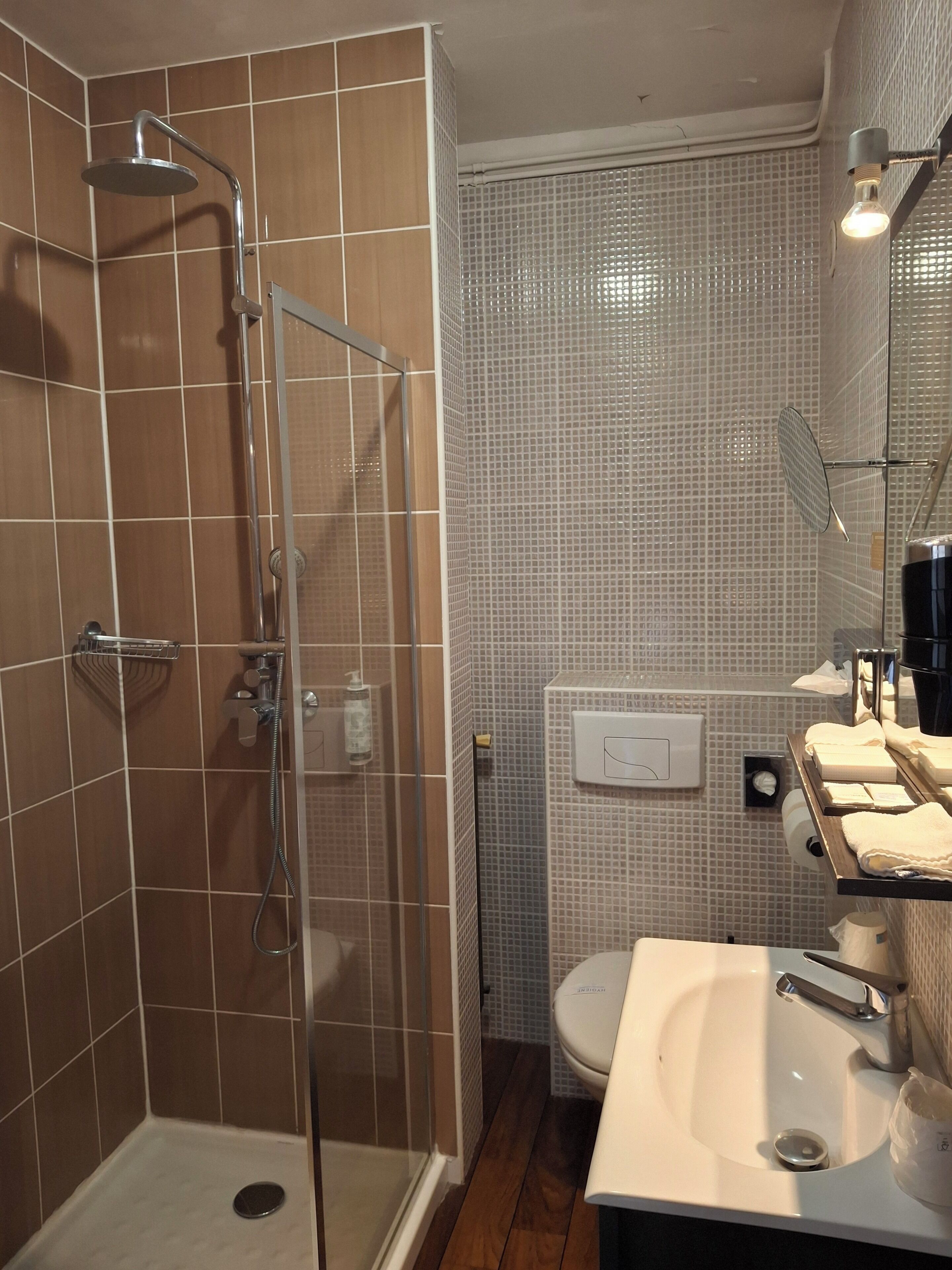 Un baño con ducha envuelta en vidrio, un lavamanos blanco y un espejo sobre él.