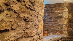 A stone wall with a metal bucket and a stone bench. - Hôtel La Tour Maje (Rodez)