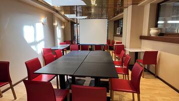 A conference room with a long table and red chairs, a whiteboard, and a window with a view of the city.