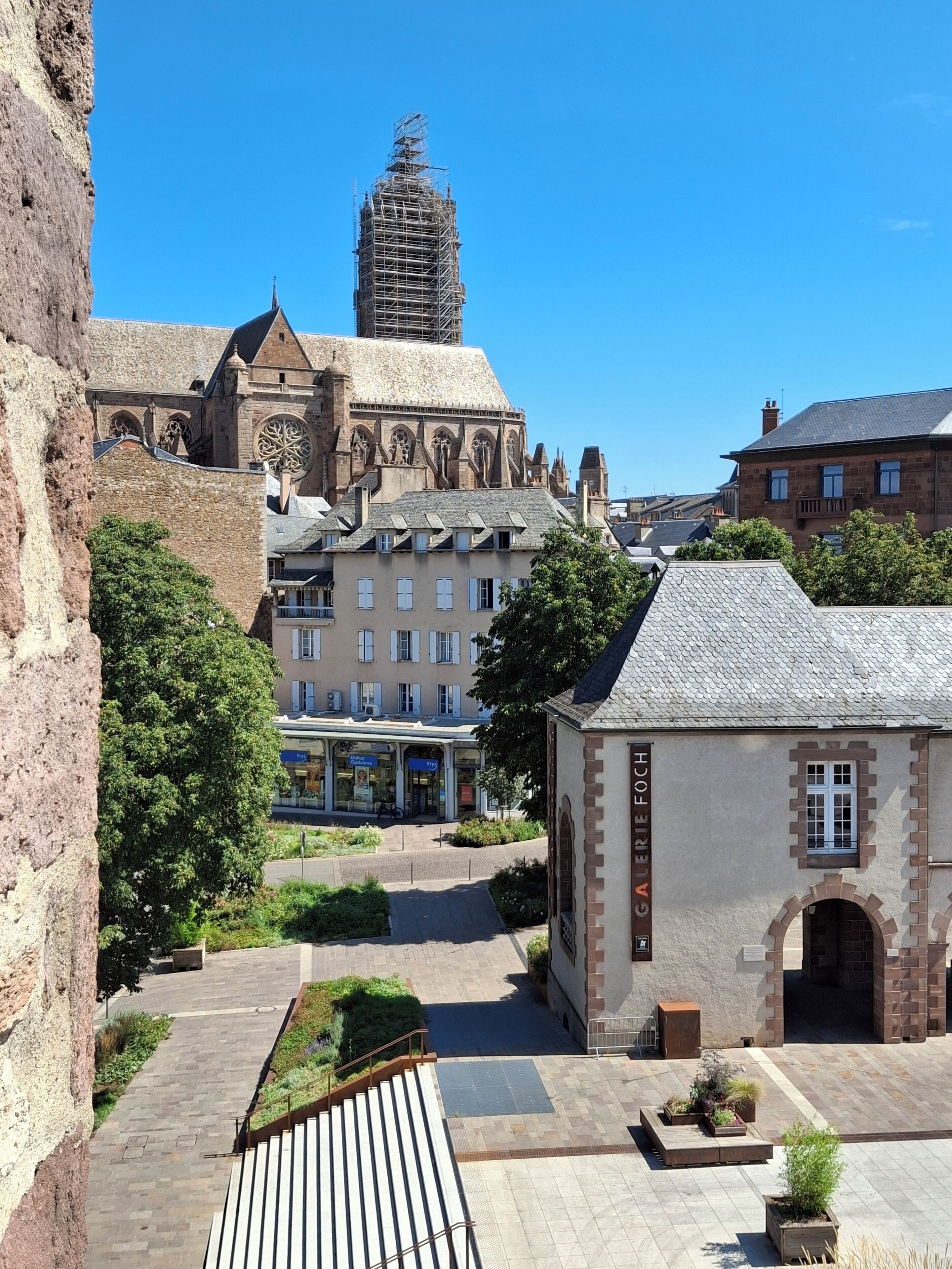 Une cour bordée d’un bâtiment historique, d’une structure moderne et d’une tour en construction.