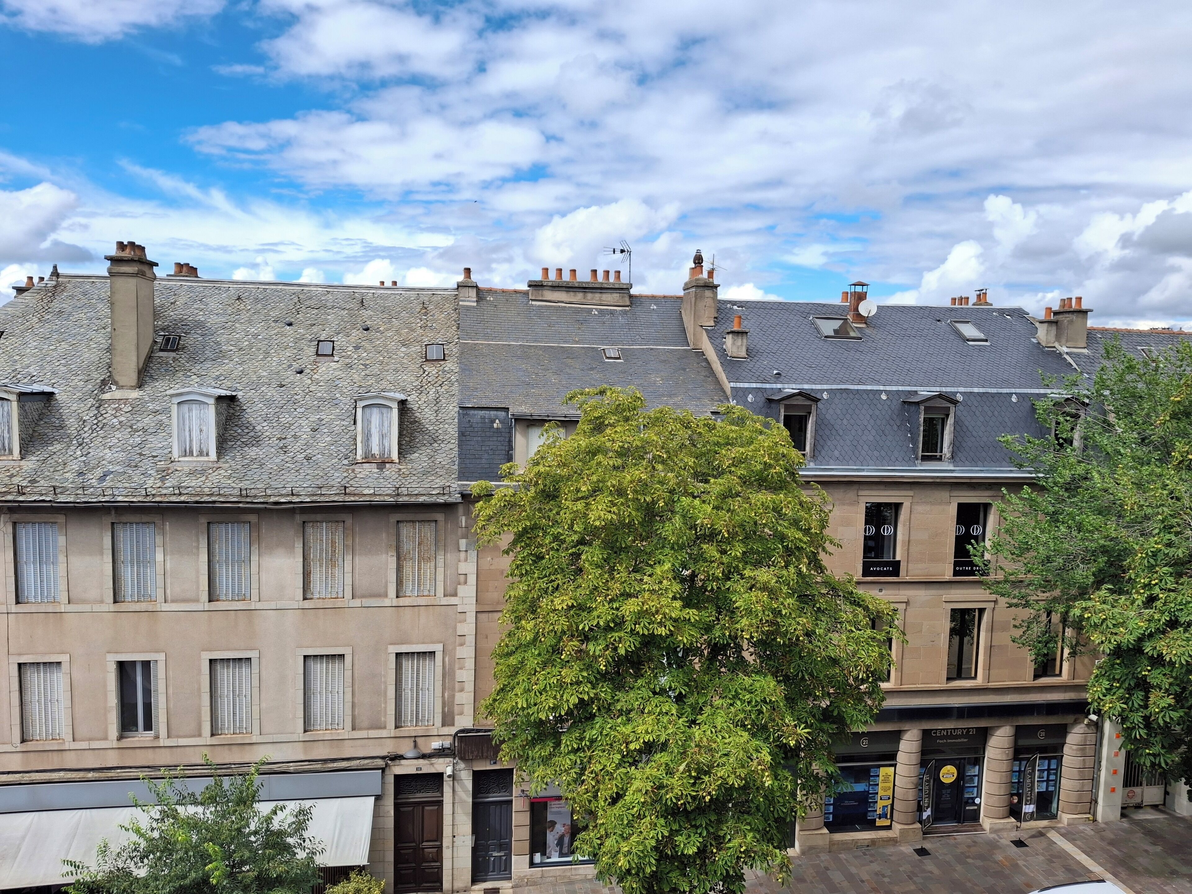 Una hilera de edificios históricos con fachadas de piedra y numerosas ventanas, algunas con contraventanas.