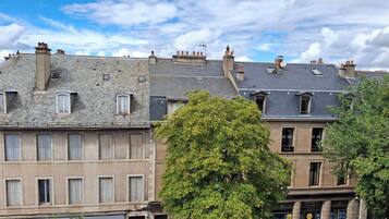 Una hilera de edificios históricos con fachadas de piedra y numerosas ventanas, algunas con contraventanas.
