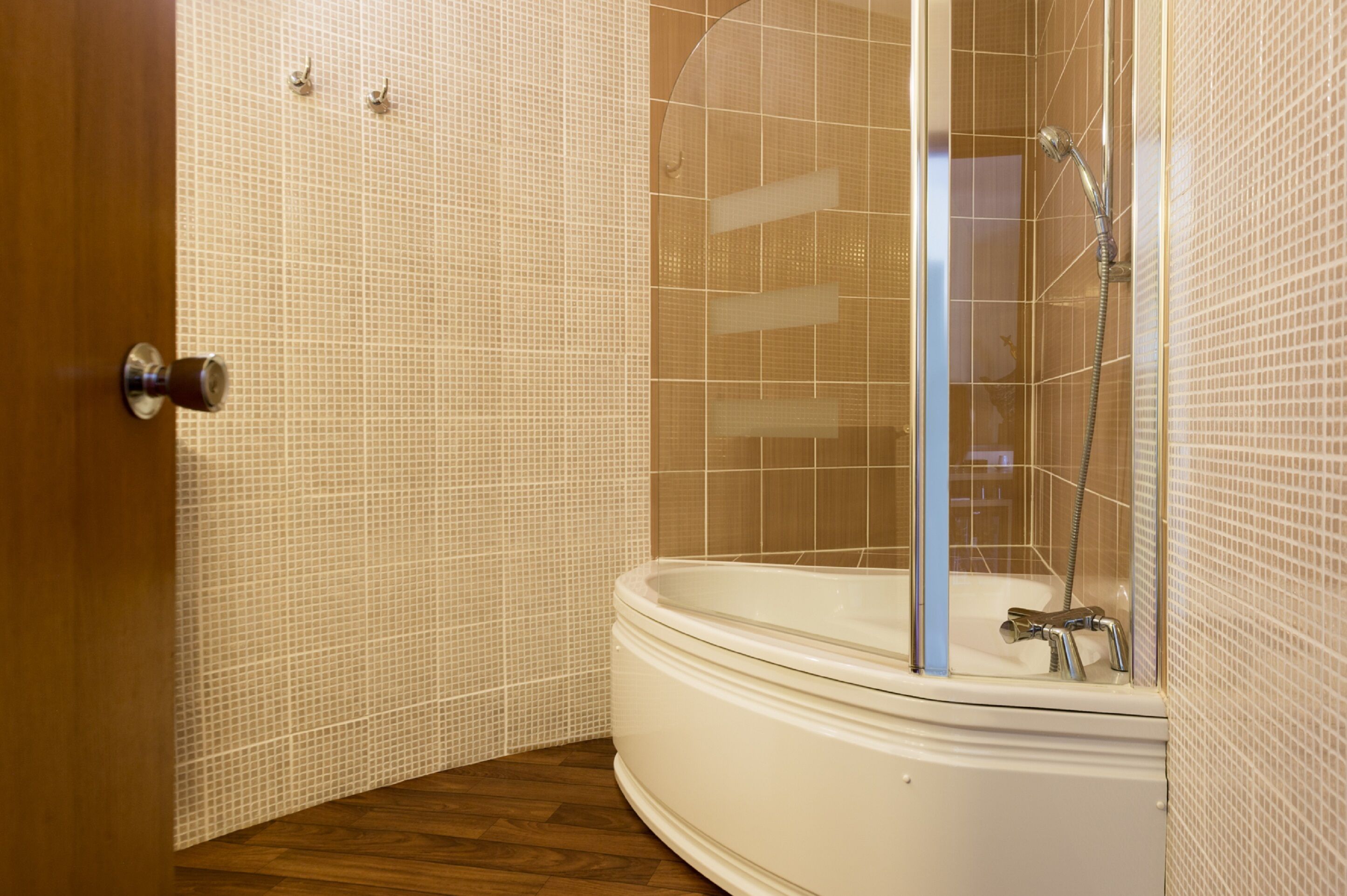 A bathroom with a shower enclosure, a bathtub, and a wooden floor.