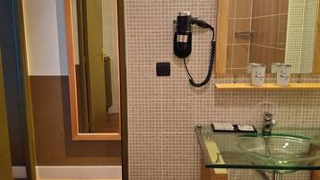 Een hotelbadkamer met een glazen wastafel, een spiegel, een telefoon en handdoeken.