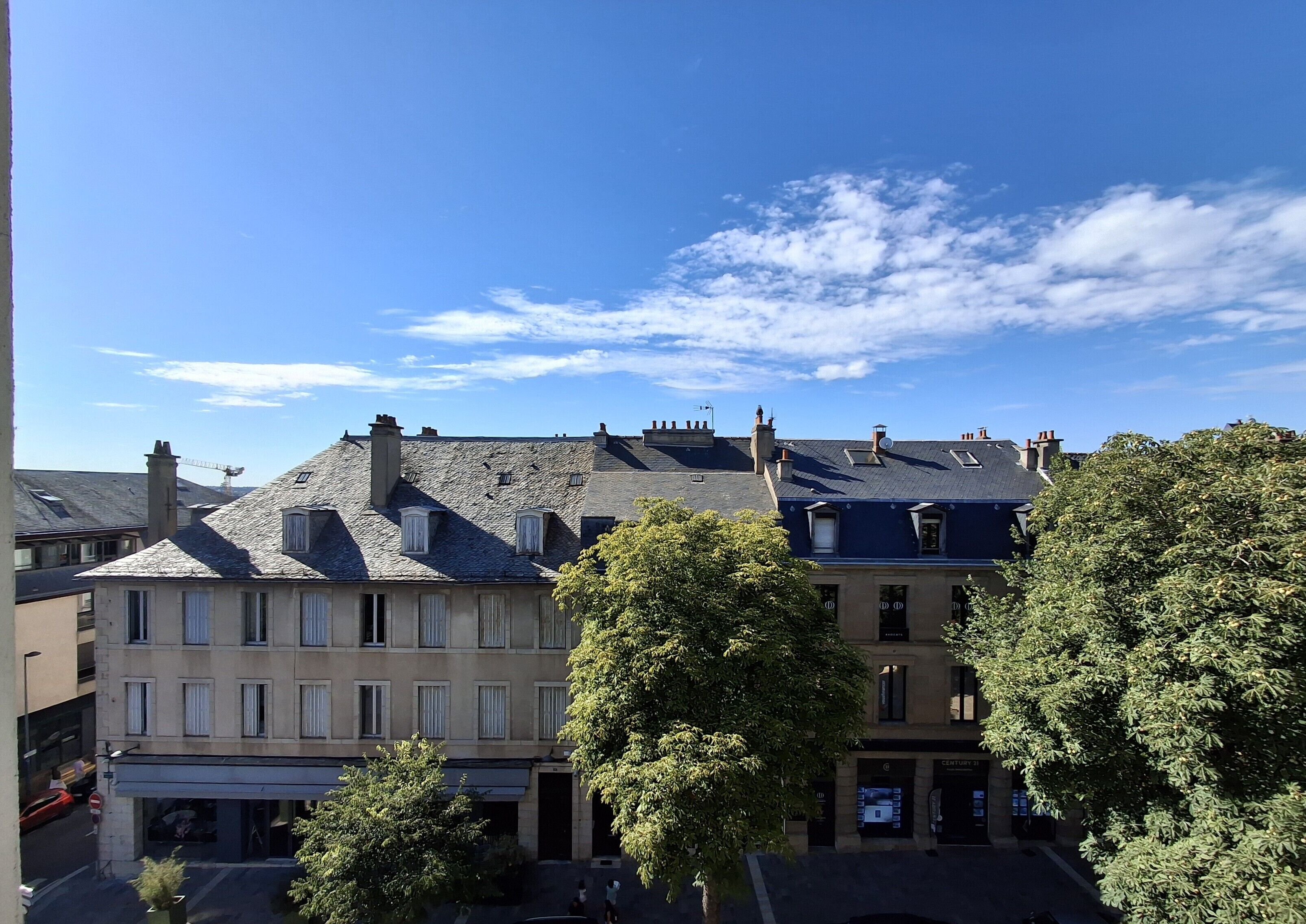 Eine Reihe von traditionellen Gebäuden im europäischen Stil mit mehreren Stockwerken, mit einer Mischung aus Stein- und Backsteinfassaden, und einem klaren, blauen Himmel darüber.