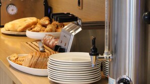 A breakfast bar with croissants, bread, and a coffee machine. - Hôtel La Tour Maje (Rodez)