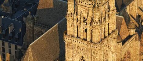 A Gothic cathedral with a prominent tower and intricate facade, surrounded by urban buildings.