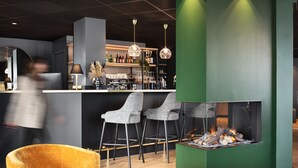 Un espace bar moderne avec un mur d’accent vert, une cheminée et des tabourets de bar.