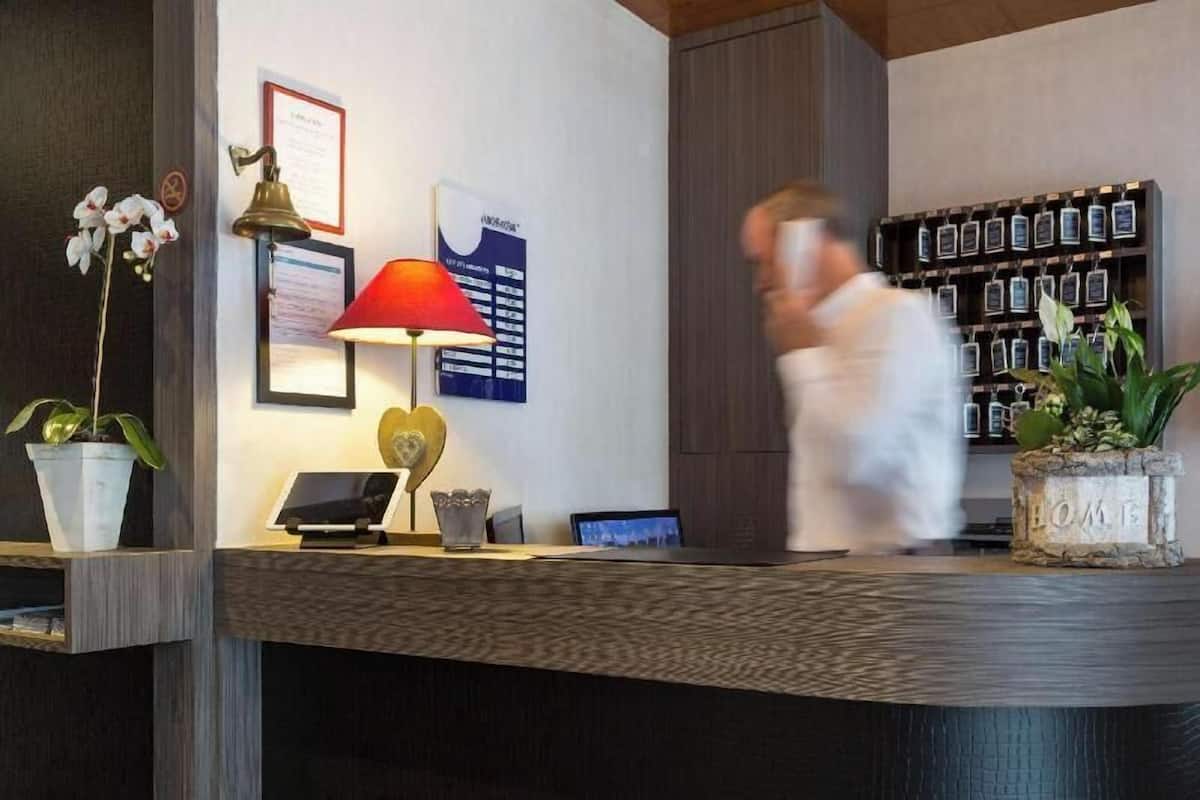 A reception desk with a lamp, a framed certificate, a laptop, and a wall-mounted display.