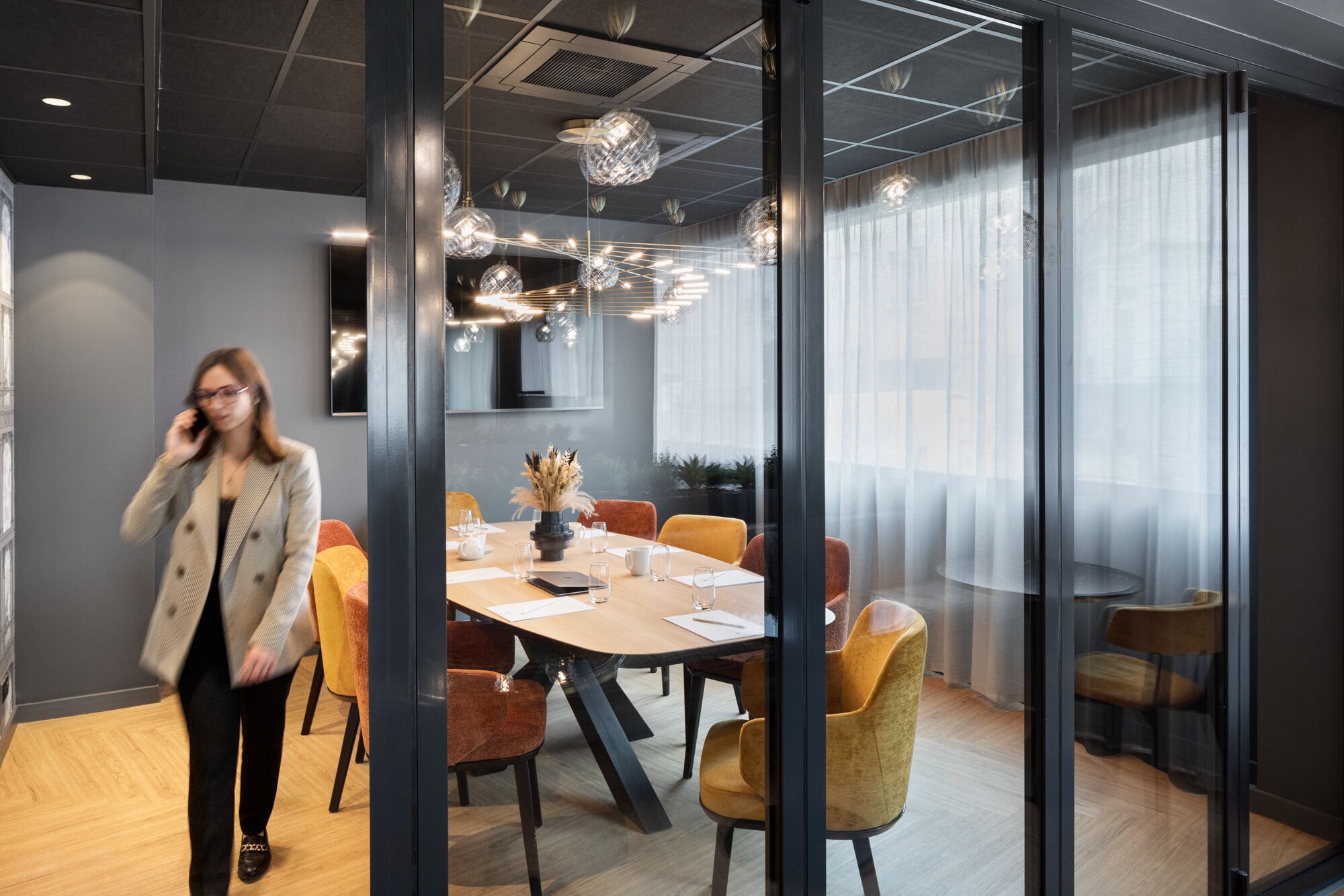 A modern conference room with a round table, chairs, and a glass partition.