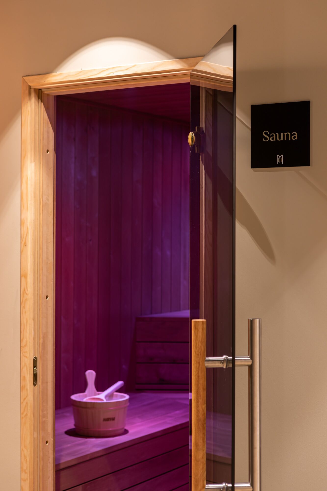 A sauna with a wooden exterior, a purple interior, and a sign that reads "Sauna".