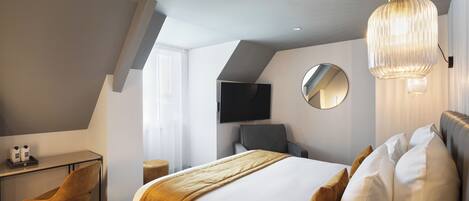 Una habitación de hotel moderna con una cama grande, un escritorio y un televisor montado en la pared.