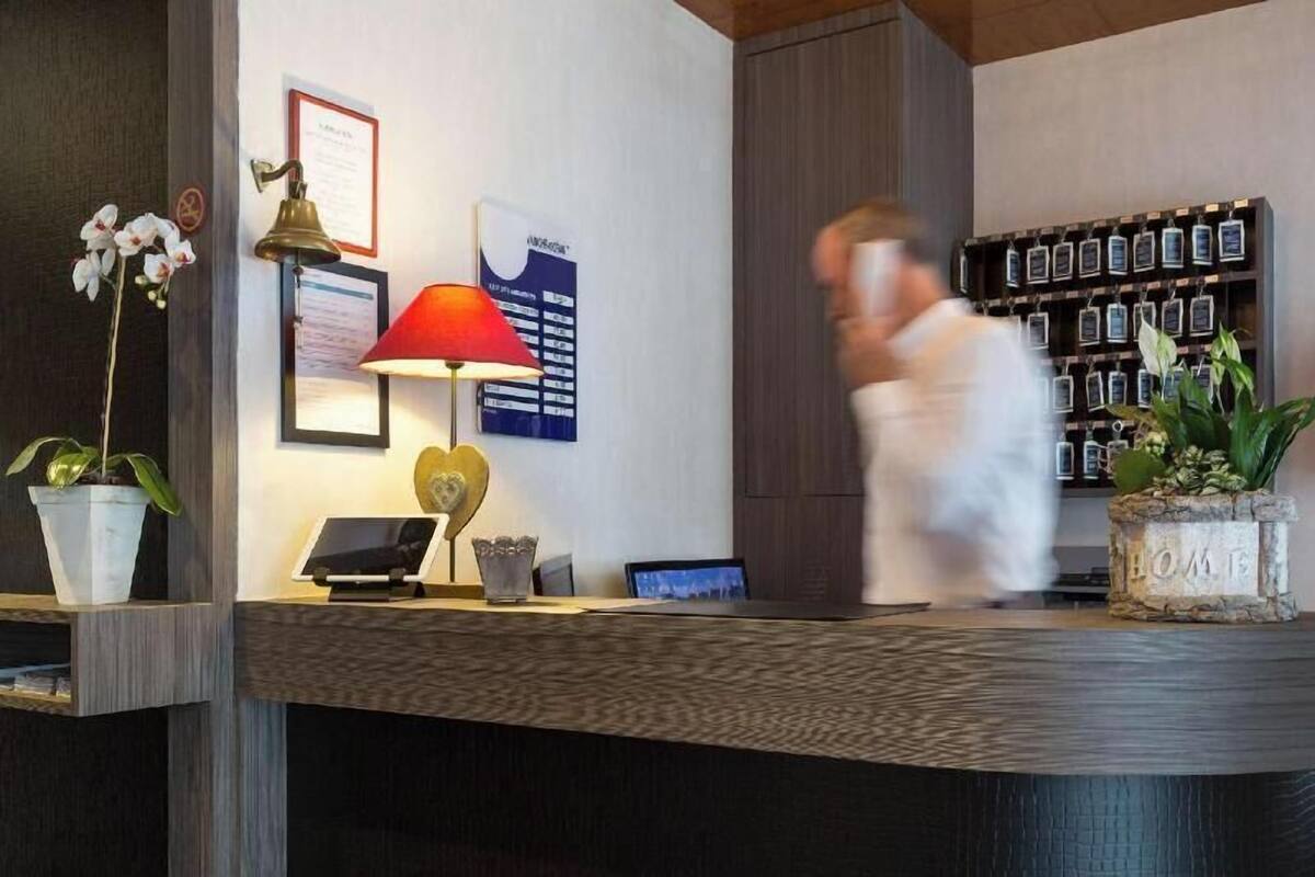 A reception desk with a lamp, a framed certificate, a laptop, and a wall-mounted display.