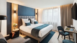 Une chambre d’hôtel moderne avec un grand lit, des tables de chevet, un bureau et une chaise.