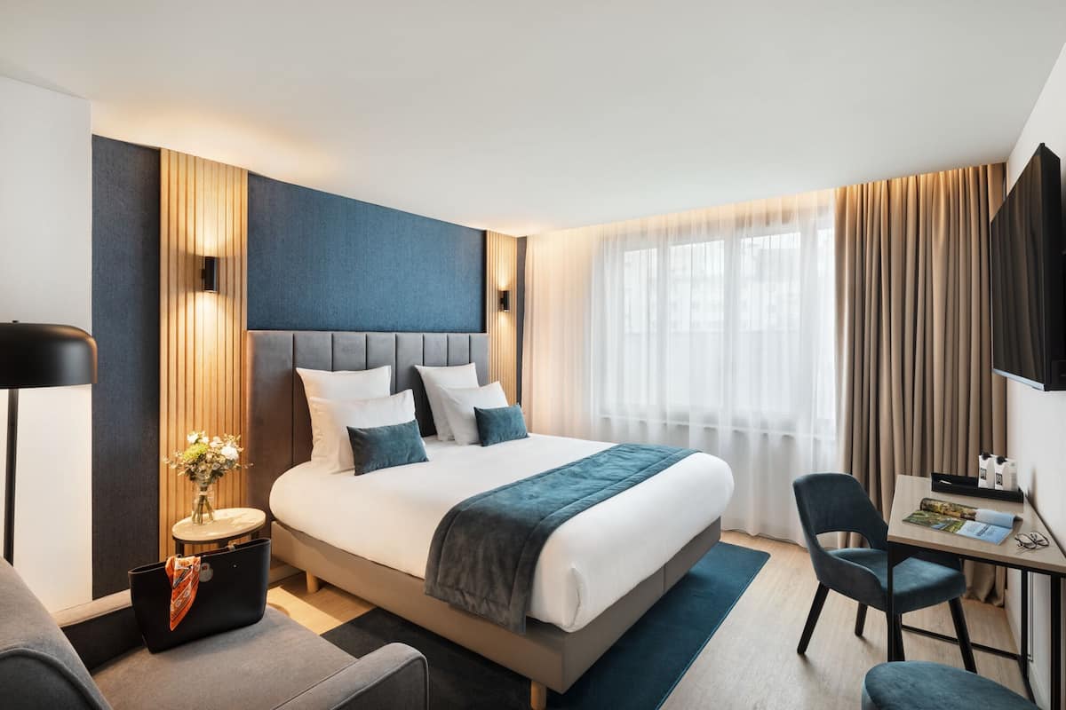 A modern hotel room with a large bed, bedside tables, a desk, and a chair.