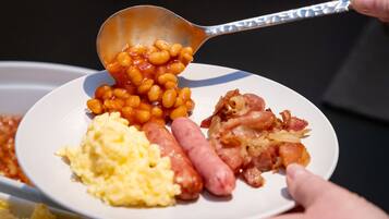 A plate with beans, sausages, and scrambled eggs.