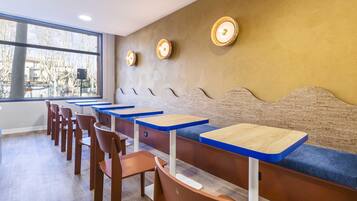 L’intérieur d’un restaurant est agrémenté de longues tables en bois, de bancs bleus rembourrés et de luminaires fixés au mur.
