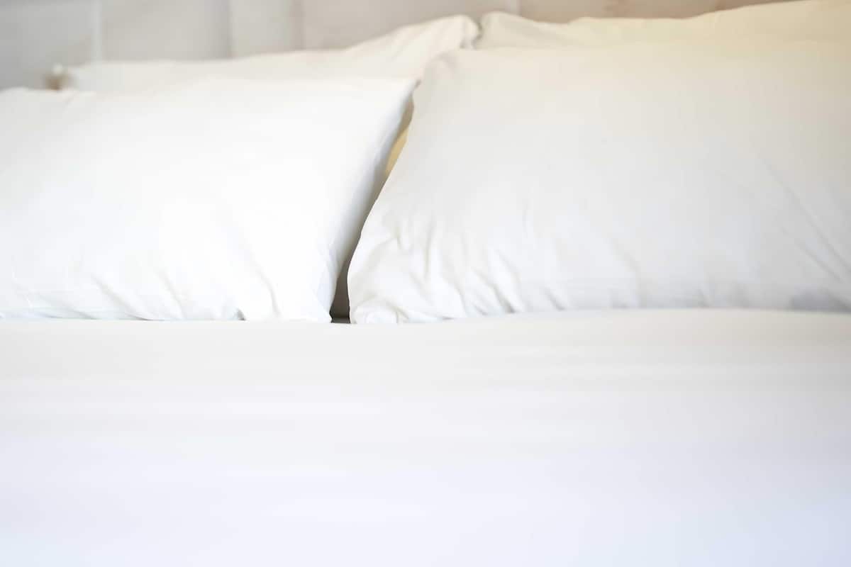 A bed with white bedding and pillows.
