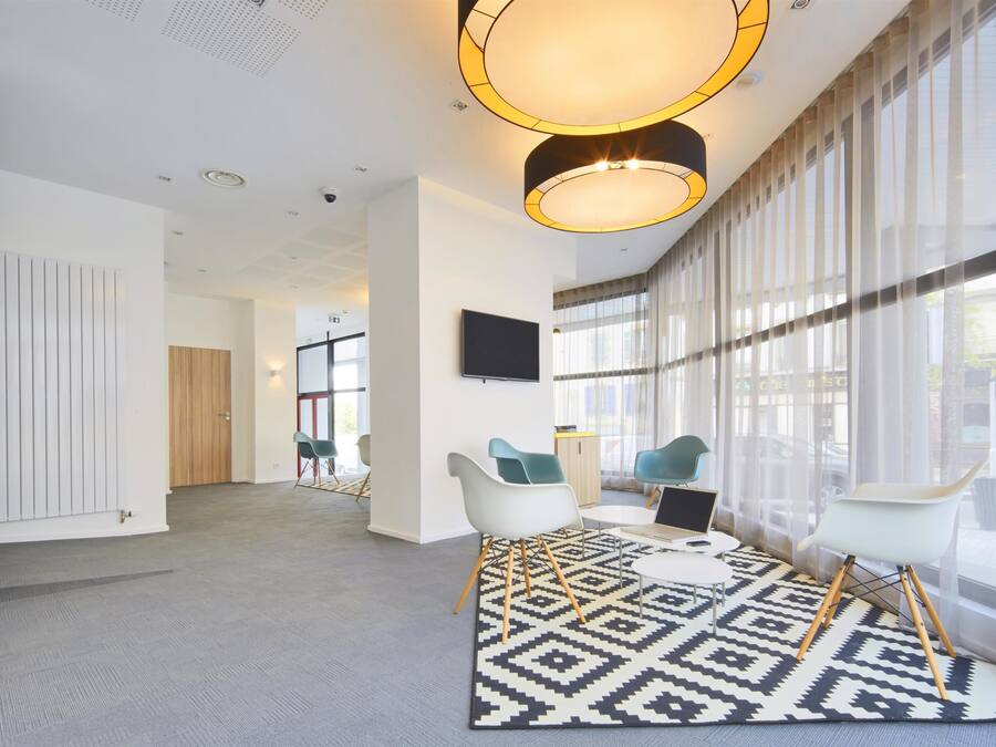 A modern office space with a large window, a patterned rug, and contemporary chairs.