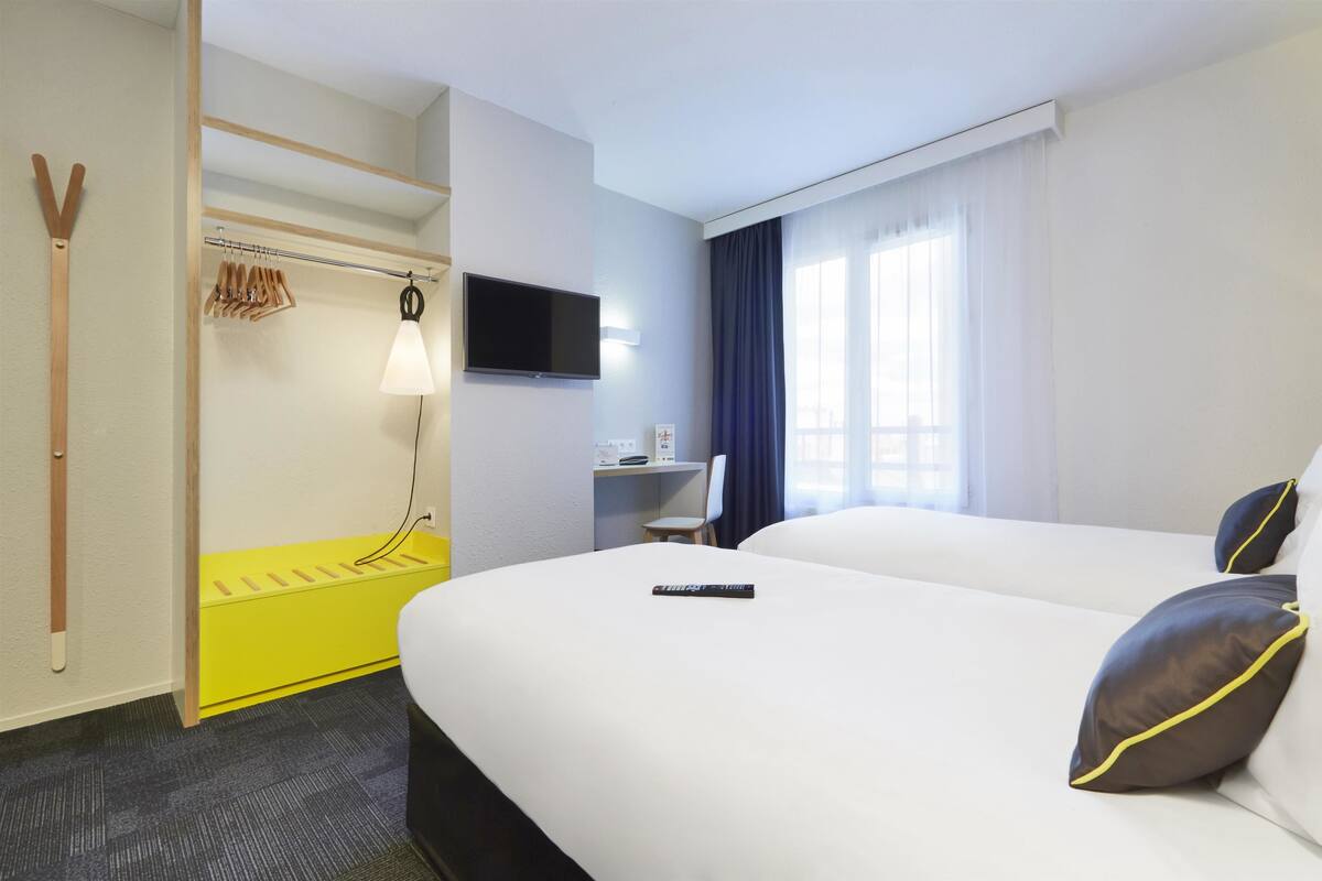 Una camera d'albergo con un letto, una televisione, una scrivania e un armadio.