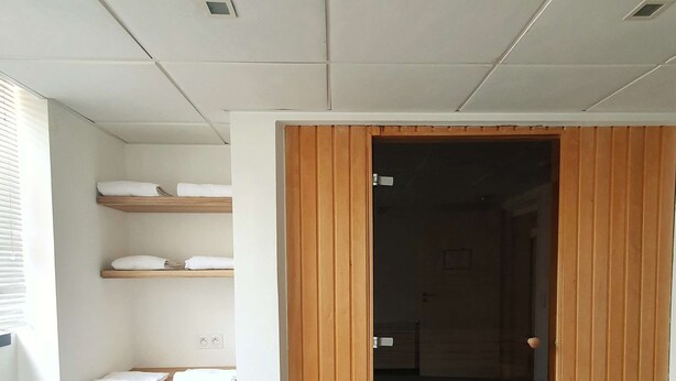 A room with a wooden wardrobe, a white bench, and a shelf with folded towels. - Kyriad Brest Centre (Brest)