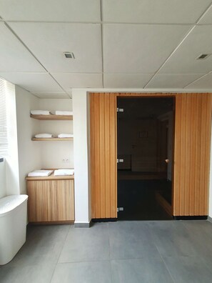 A room with a wooden wardrobe, a white bench, and a shelf with folded towels. - Kyriad Brest Centre (Brest)