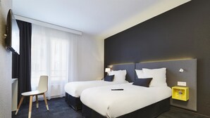 A hotel room with two beds, a desk, a chair, a TV, and a bedside table with a lamp. - Kyriad Brest Centre (Brest)