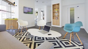 A modern hotel lobby with a reception desk, seating area, and a bookshelf. - Kyriad Brest Centre (Brest)