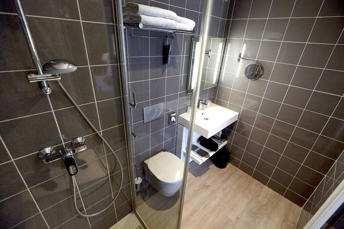 Un bagno moderno con doccia vetro, un water e un lavandino con specchio sopra.