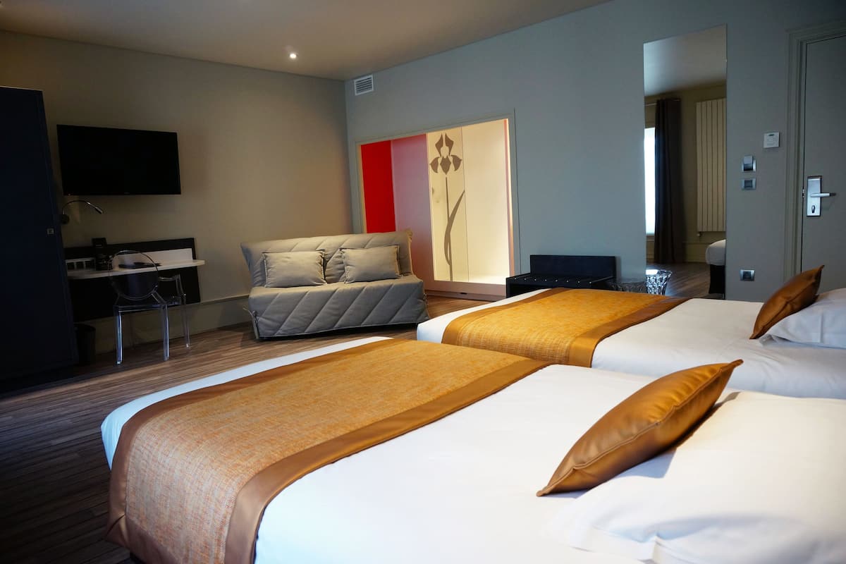 A hotel room with two beds, a desk, a chair, a TV, and a large mirror.