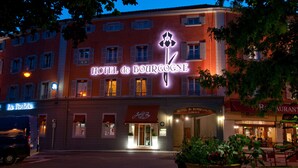 The exterior of Hotel de Bourgogne with illuminated signage, a visible entrance, and surrounding greenery. - Hôtel de Bourgogne (Macon)