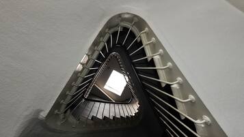Una escalera de caracol con barandillas metálicas y un tragaluz en la parte superior.