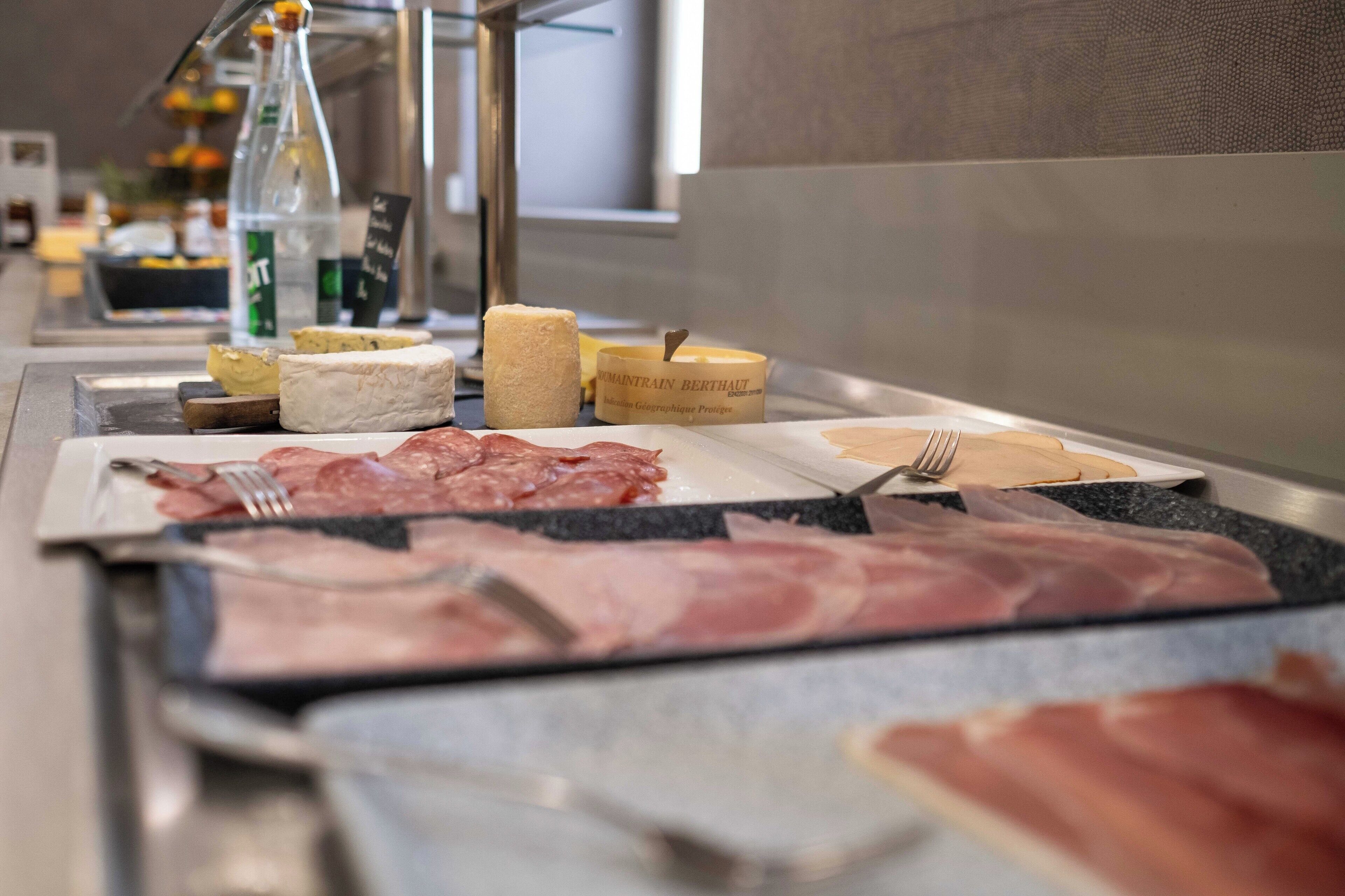 A buffet with various meats and cheeses.