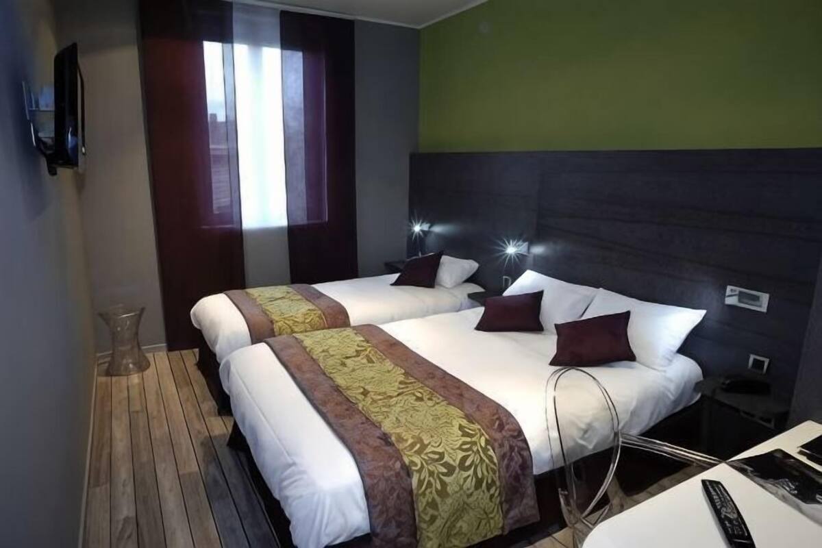 A hotel room with two beds, a TV, a window, and a desk with a chair.